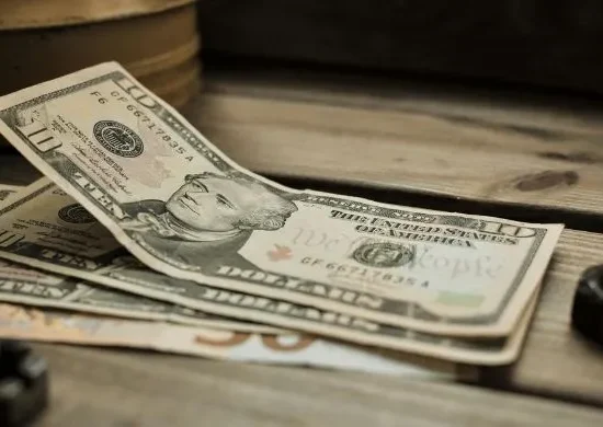 Stack of US dollar banknotes placed on a wooden surface, representing financial transactions and foreign exchange reserves amid Pakistan’s repayment of a $1 billion deposit to the UAE.
