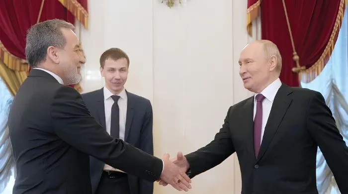 Russian President Vladimir Putin shakes hands with Iranian Foreign Minister Abbas Araghchi during a formal meeting, highlighting diplomatic engagement and Russia’s support for Iran amid ongoing tensions with the US.