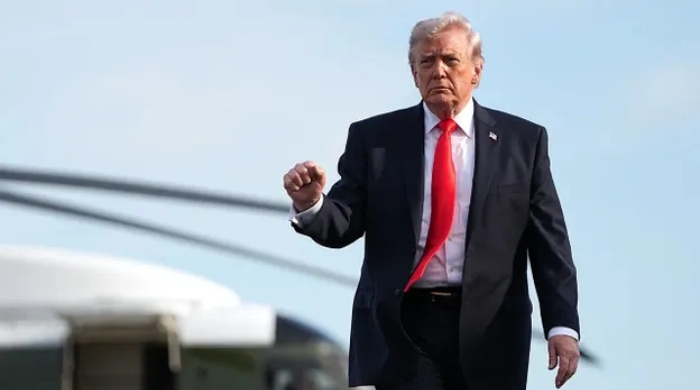 US President Donald Trump walks near a military aircraft, reflecting the decision to pause the Strait of Hormuz operation amid diplomatic efforts involving Pakistan and Iran.
