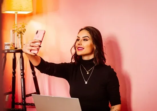Influencer taking a selfie with a laptop, symbolizing Pakistan’s new 5% tax on digital content creators.